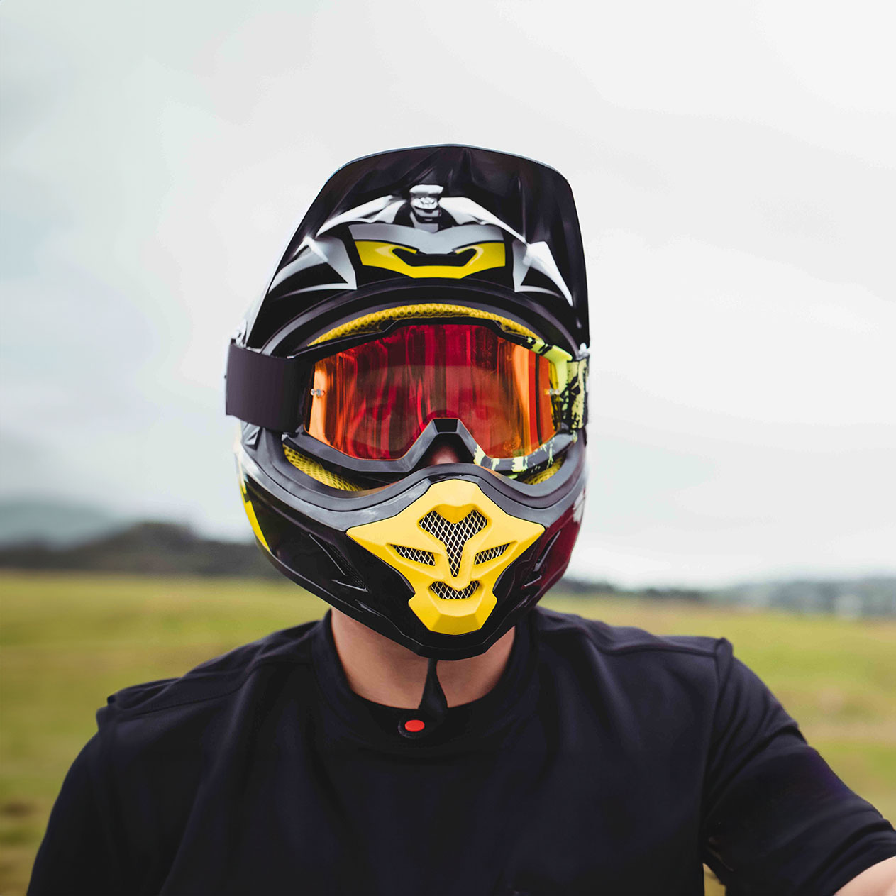 A person wearing a protective helmet and goggles in a field.